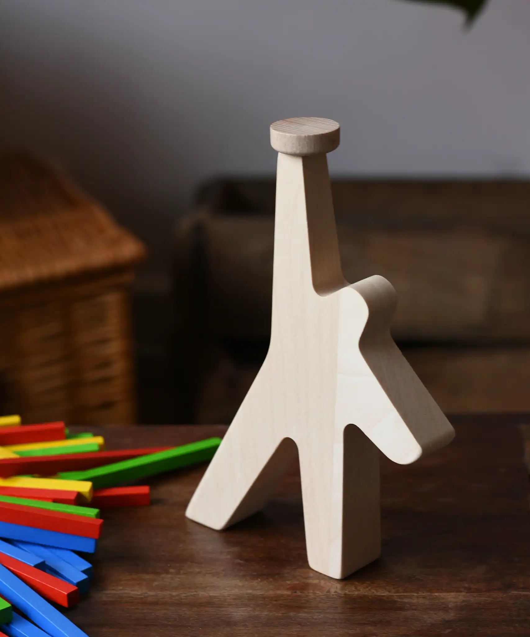 Athlete shaped wooden figure base from the Bajo athlete wooden stacking balance game placed on a wooden surface with the wooden sticks placed besides it.
