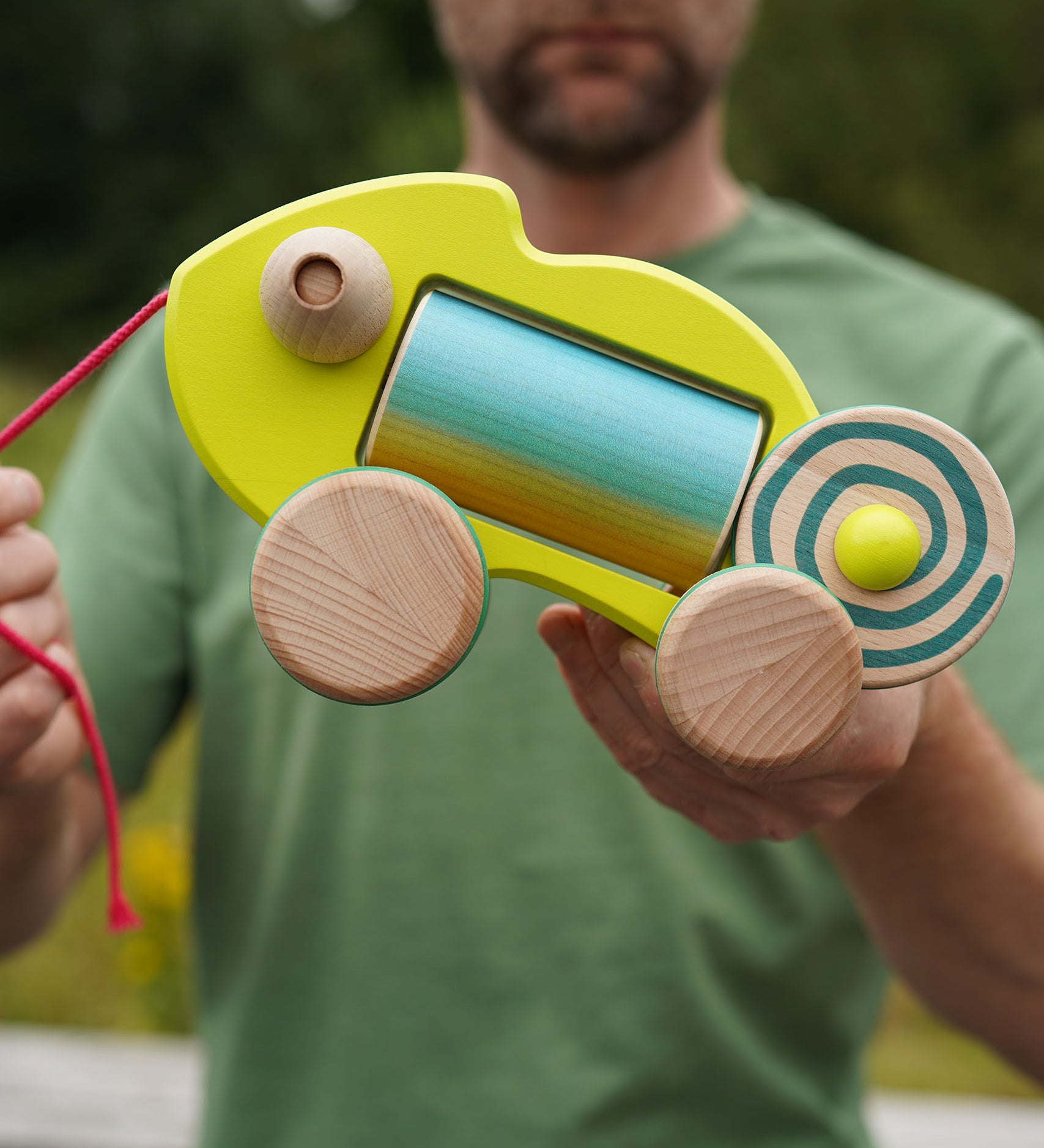 Person holding a colorful wooden chameleon baby toy