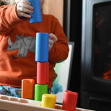 A child stacking the blocks from the Bajo Balance Scale wooden toy on top of each other. A wooden base with a curved base with coloured wooden blocks that sit on top. These heirloom quality toys by Bajo are part of a wide range of wooden toys available here at Babipur.