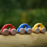 A group of Bajo handmade wooden beetle style car including blue, yellow and red available at Babipur - photo on a outdoor background.