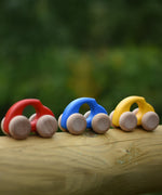 A group of Bajo handmade wooden beetle style car including blue, yellow and red available at Babipur - photo on a outdoor background.