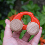 An adult hand holding the Bajo handmade wooden beetle style car in red available at Babipur showing scale of the vehicle