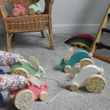 A child playing with a collection of 4 big Bajo pull along rabbit toys. One pink, one mint green, one light blue and one white. These heirloom quality toys by Bajo are part of a wide range of wooden toys available here at Babipur.