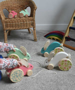 A child playing with a collection of 4 big Bajo pull along rabbit toys. One pink, one mint green, one light blue and one white. These heirloom quality toys by Bajo are part of a wide range of wooden toys available here at Babipur.