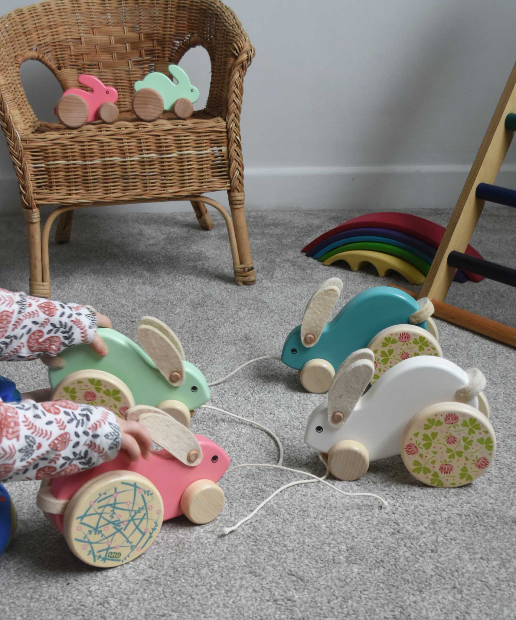A child playing with a collection of 4 big Bajo pull along rabbit toys. One pink, one mint green, one light blue and one white. These heirloom quality toys by Bajo are part of a wide range of wooden toys available here at Babipur.