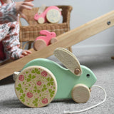 The mint Bajo big rabbit placed on the floor in front of a Triclimb Miri slide. A child can be seen in the background placing a pink coloured small push along rabbit on the Miri slide. These heirloom quality toys by Bajo are part of a wide range of wooden toys available here at Babipur.