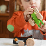 A Bajo Pull-Back black Caterpillar Toy placed on a table in front of a child. A black coloured caterpillar toy that has a yellow eye and natural wooden wheels.  These heirloom quality toys by Bajo are part of a wide range of wooden toys available here at Babipur.