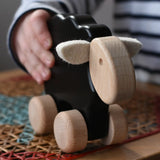 Child playing with the Bajo black sheep push along wooden toy on wheels in the Babipur playroom.