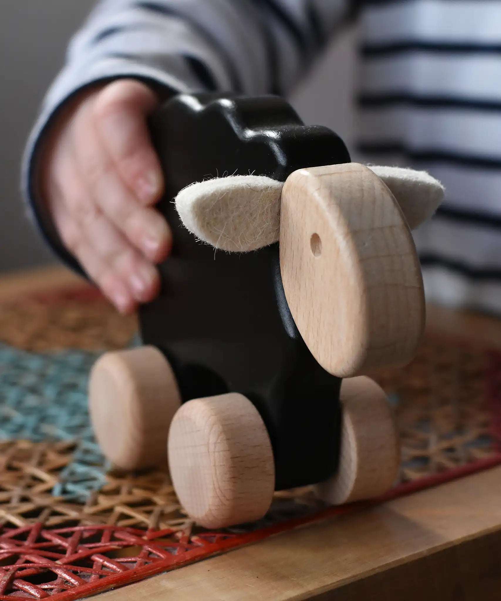 Child playing with the Bajo black sheep push along wooden toy on wheels in the Babipur playroom.