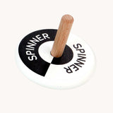 Bajo black and white Spinning Top. A black and white monochrome wooden spinning top with a natural wooden stick with the word spinner written on each half of the circle top.