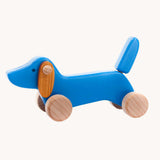 A blue coloured Bajo dachshund puppy wooden toy on wheels. These heirloom quality toys by Bajo are part of a wide range of wooden toys available here at Babipur.