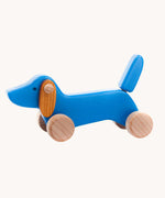 A blue coloured Bajo dachshund puppy wooden toy on wheels. These heirloom quality toys by Bajo are part of a wide range of wooden toys available here at Babipur.
