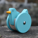 Bajo blue wobbling chicken push along toy placed on a stone wall.