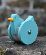 Bajo blue wobbling chicken push along toy placed on a stone wall.