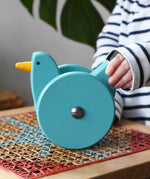 Child playing with the Bajo blue wobbling chicken push along toy.