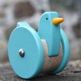 Front of the Bajo blue wobbling chicken push along toy placed on a stone wall.