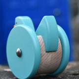 Back of the Bajo blue wobbling chicken push along toy placed on a stone wall.