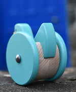 Back of the Bajo blue wobbling chicken push along toy placed on a stone wall.