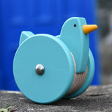 Bajo blue wobbling chicken push along toy placed on a stone wall.
