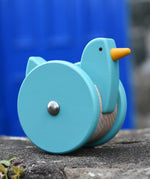 Bajo blue wobbling chicken push along toy placed on a stone wall.