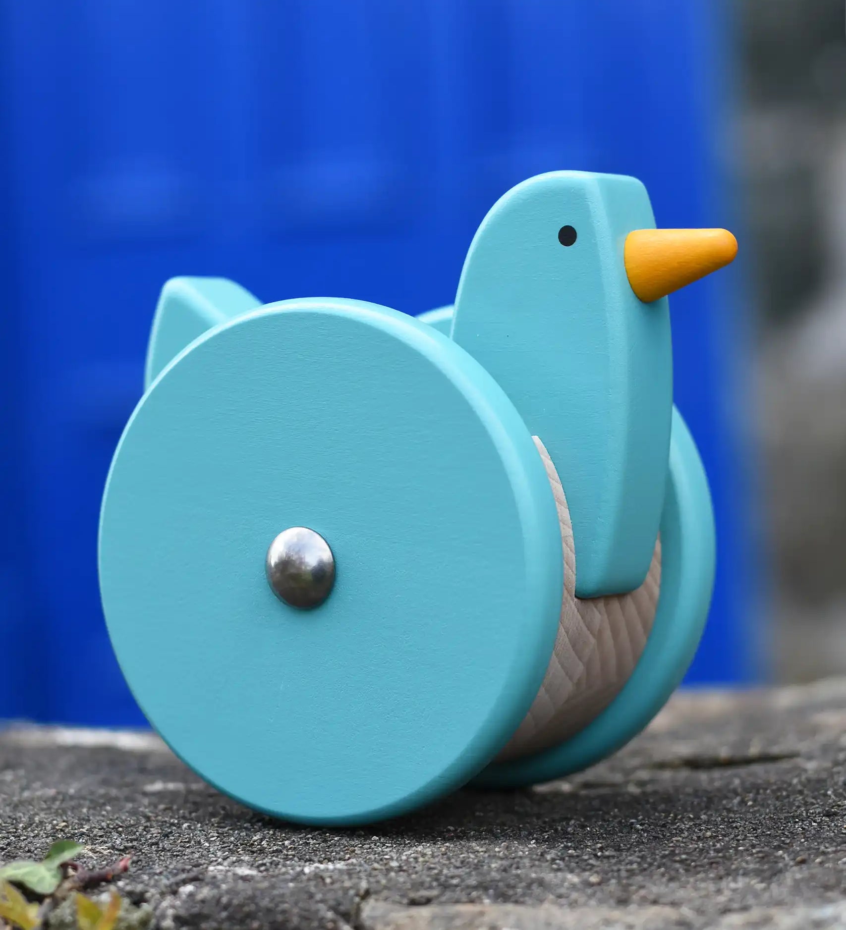 Bajo blue wobbling chicken push along toy placed on a stone wall.