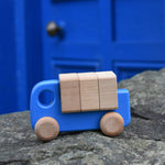 A blue coloured Bajo truck with blocks placed on a stone wall