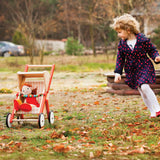 Child playing with Bajo's buggy on grass showing a doll sitting inside the buggy