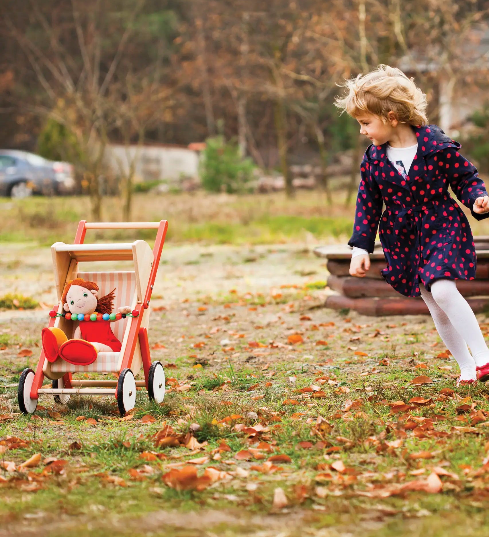 Child playing with Bajo's buggy on grass showing a doll sitting inside the buggy