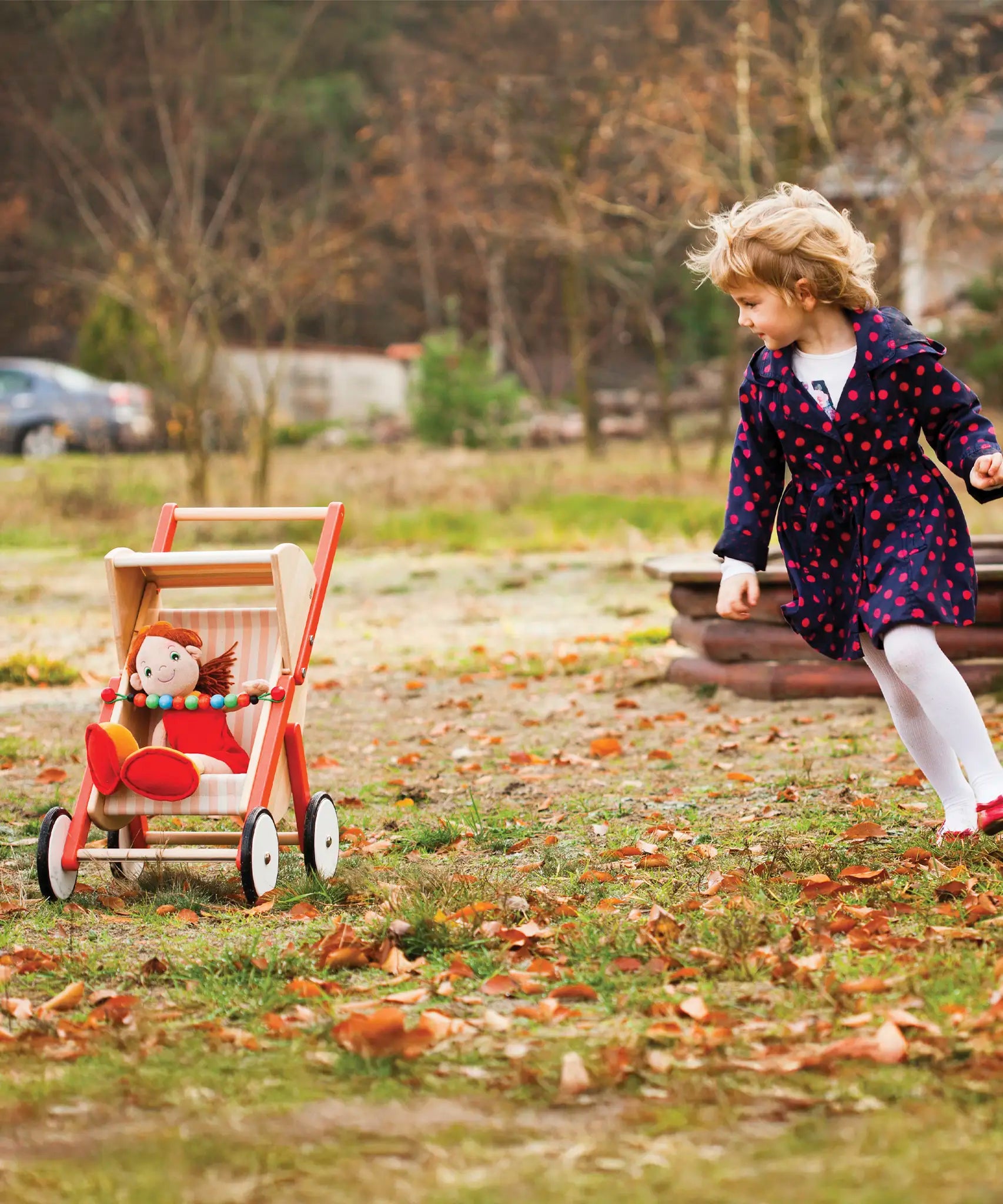 Child playing with Bajo's buggy on grass showing a doll sitting inside the buggy