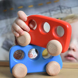 A child's hand holding a red coloured bus, the child is placing it on a blue coloured bus. These heirloom quality toys by Bajo are part of a wide range of wooden toys available here at Babipur. 