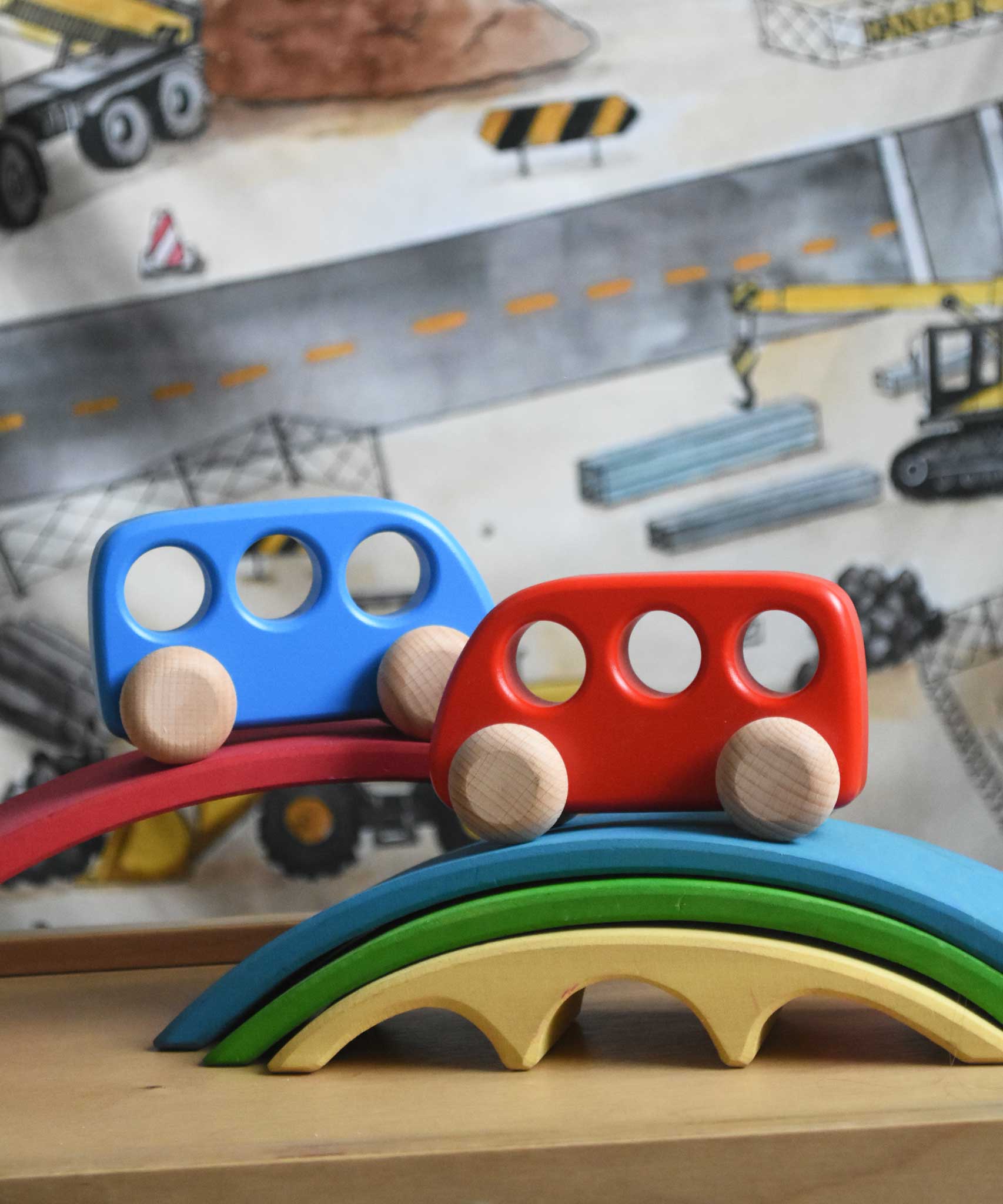 A blue and red Bajo wooden push along bus toy placed on pieces of the Gluckskafer bridge. These heirloom quality toys by Bajo are part of a wide range of wooden toys available here at Babipur. 