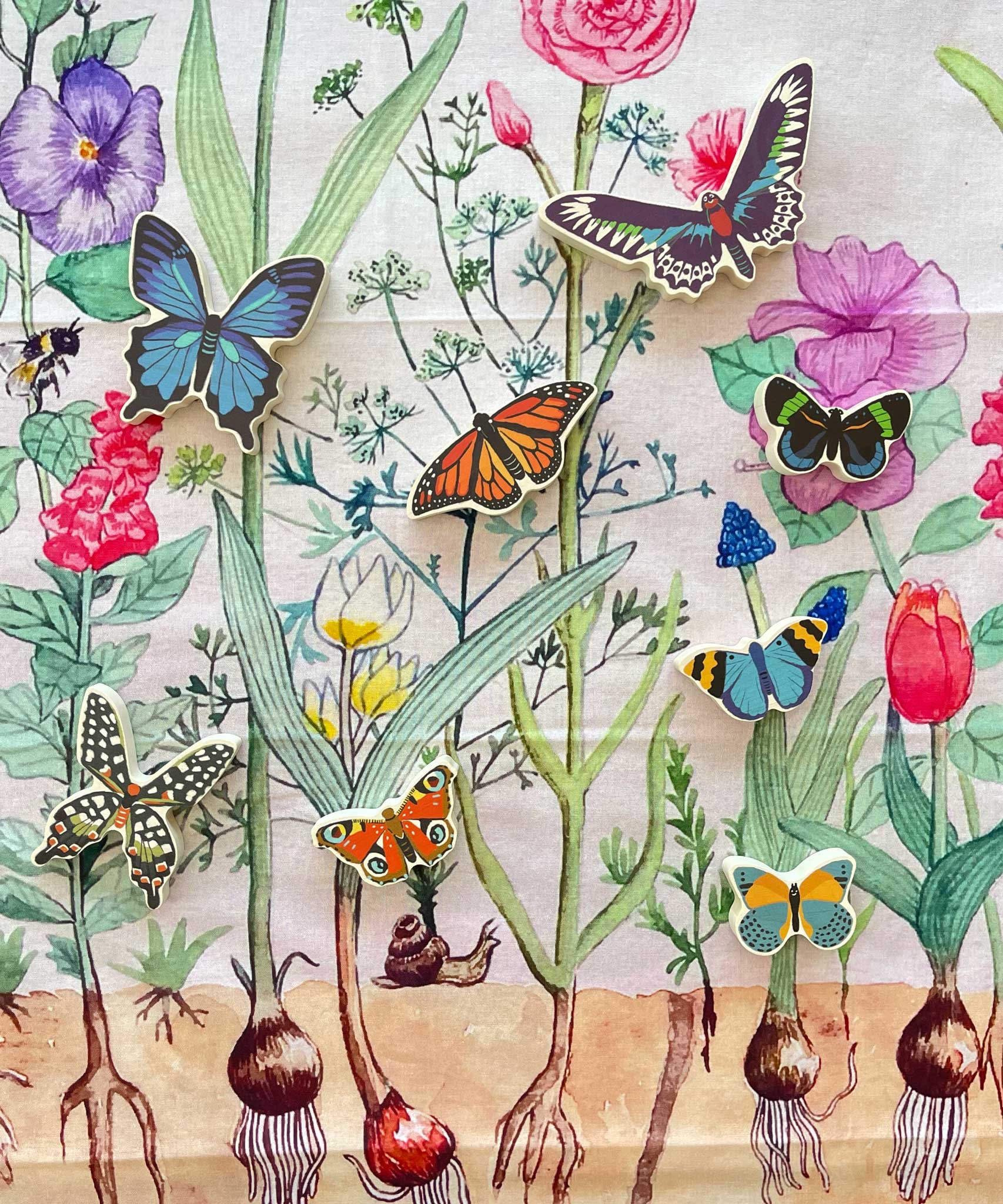 The butterfly shaped pieces from the Bajo World Of Butterflies Sorter Puzzle placed on a Wonderie play cloth. This puzzle has butterfly shaped pieces that are decorated on both sides that slot into the coordinating shapes on the base. These heirloom quality toys by Bajo are part of a wide range of wooden toys available here at Babipur.