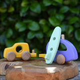 Bajo yellow car and purple camper wooden toy vehicle with green surfboard. the green surfboard is being rested against the camper/