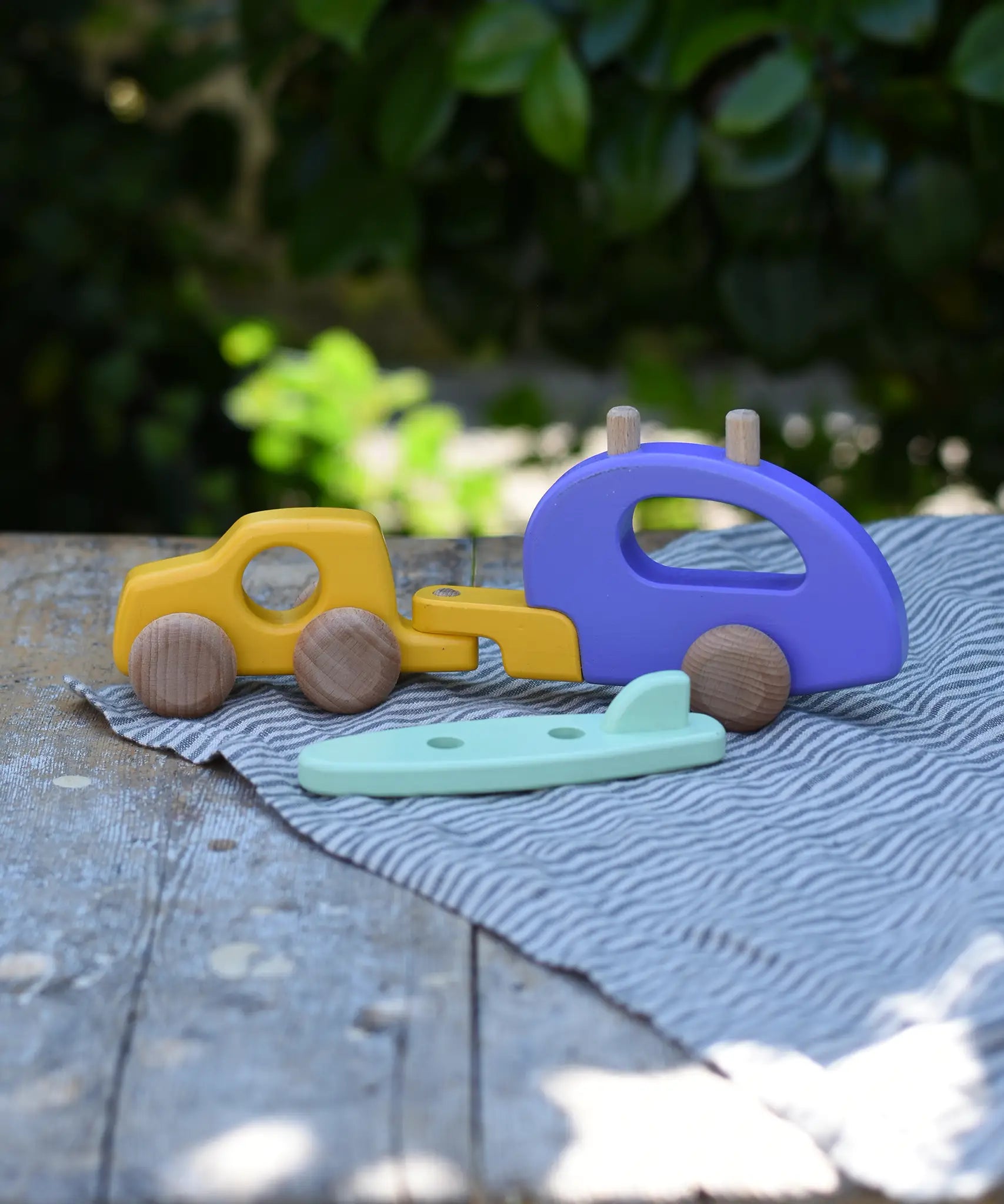 Bajo yellow car and purple camper wooden toy vehicle with the mint green surfboard taken off the roof rack.