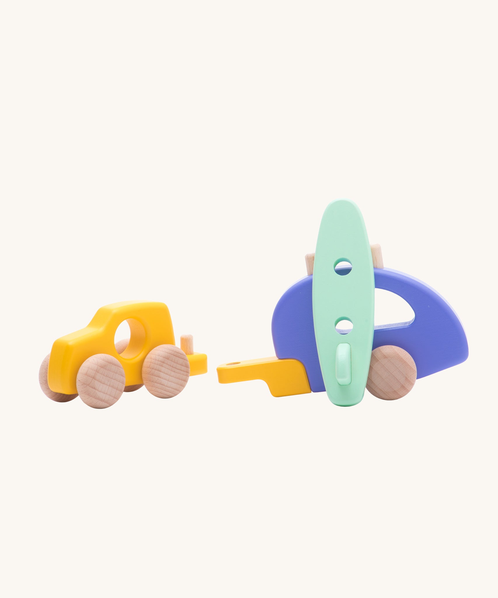 Bajo Car and Camper wooden toy with the pieces detached from each other. There is a yellow car, purple camper trailer and a mint green coloured surf board. These heirloom quality toys are part of a wode range of Bajo wooden toys available here at Babipur.