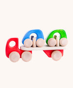 A red coloured Bajo wooden toy car transporter available at Babipur. This red coloured truck has natural wooden wheels and comes with two mini cars, one blue and one green.