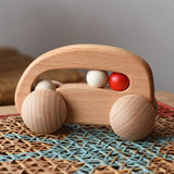 Bajo natural wooden car with beads push along toy on a rattan stool in the  Babipur playroom. 