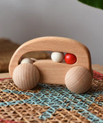 Bajo natural wooden car with beads push along toy on a rattan stool in the  Babipur playroom. 