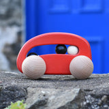 Bajo red wooden toy car with beads push along toy placed on a stone wall outdoors. 