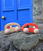 Bajo wooden toy cars with beads push along toys placed on a stone wall outdoors. 