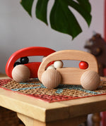 Bajo wooden toy cars with beads push along toys placed on a rattan stool in the Babipur playroom.