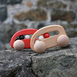 Bajo wooden toy cars with beads push along toys placed on a stone wall outdoors. 
