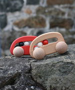 Bajo wooden toy cars with beads push along toys placed on a stone wall outdoors. 