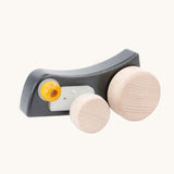 Bajo Pull-Back Caterpillar Toy. A black coloured caterpillar toy that has a yellow eye and natural wooden wheels. 