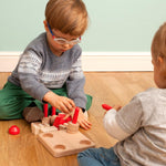 Two children sat on a wooden floor playing with the Bajo plastic-free castle stacking toy