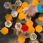 Close up of a hand playing with the Bajo plastic-free hive block toys on a wooden log