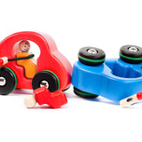 Red and blue Bajo eco-friendly wooden fasten seat belt cars on a wooden background behind some grey wooden counters.