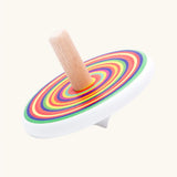 Bajo colourful circles spinning top wooden toy. White painted wooden base with a rainbow stripe decorated top and a natural wood handle.