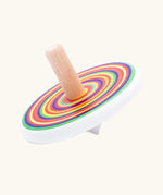 Bajo colourful circles spinning top wooden toy. White painted wooden base with a rainbow stripe decorated top and a natural wood handle.