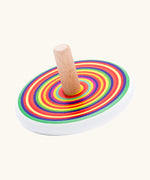Bajo colourful circles spinning top wooden toy. White painted wooden base with a rainbow stripe decorated top and a natural wood handle.